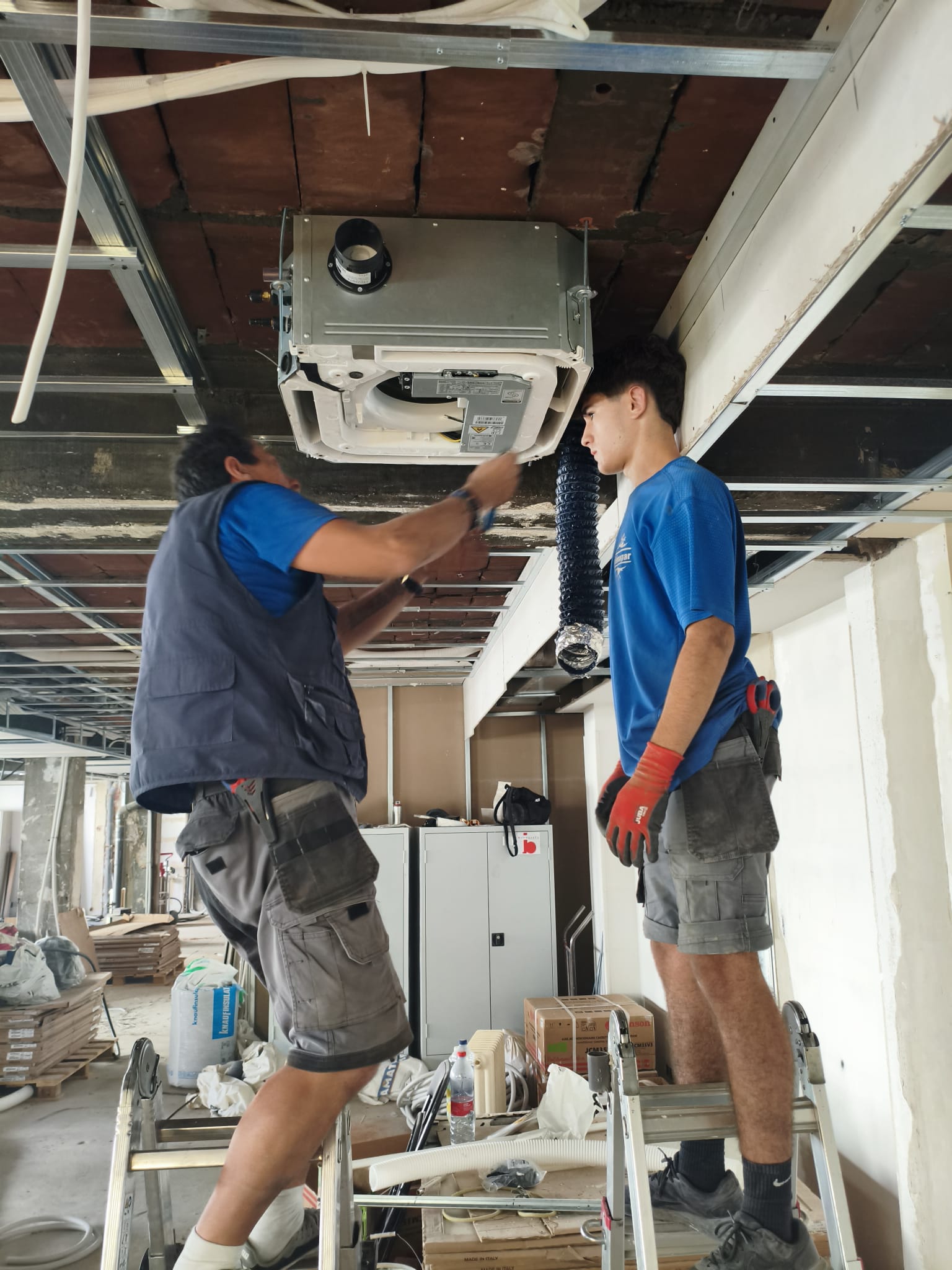 Técnicos de Climagar instalando un cassette Daikin en el falso techo de un local en Móstoles